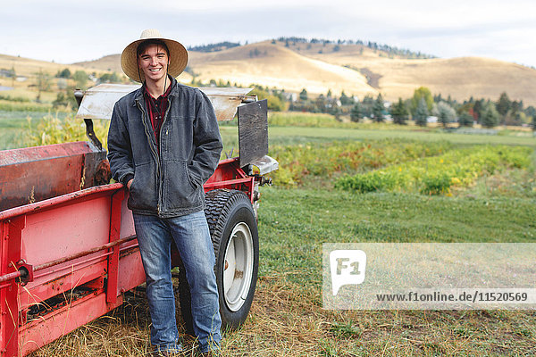 Portrait of young man standing beside tractor  Missoula  Montana  USA