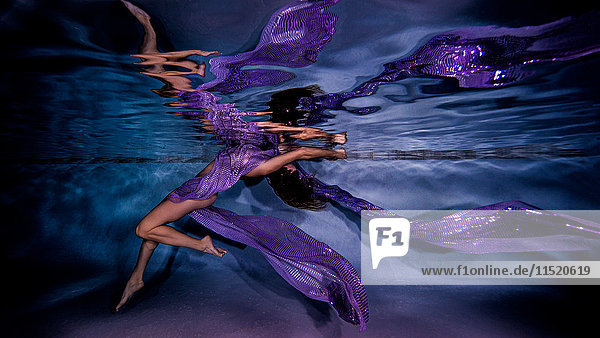 Mature woman draped in sheer fabric  underwater view