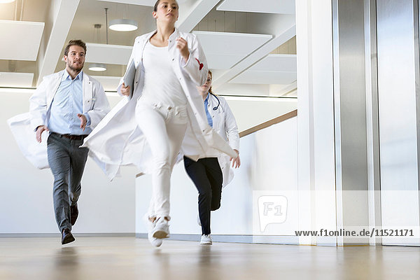 Male and female doctors running along hospital corridor