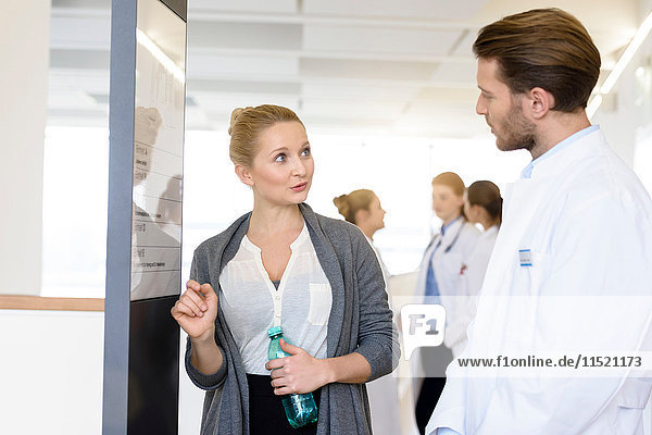 Frau und männlicher Arzt diskutieren im Krankenhauskorridor