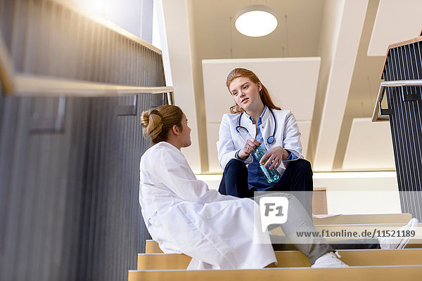 Zwei Ärztinnen machen eine Pause im Gespräch auf der Krankenhaustreppe