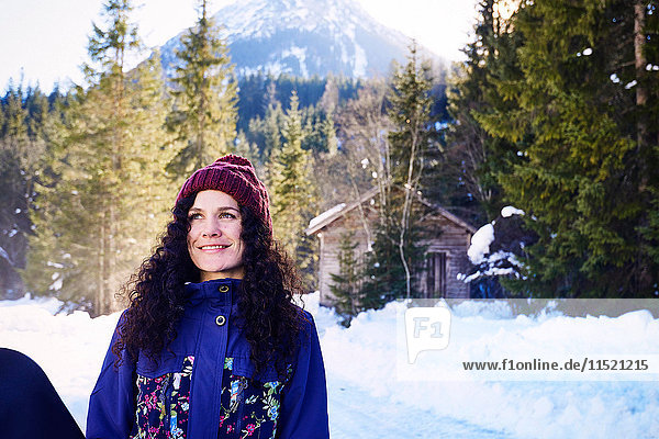 Frau mit Strickmütze beim Blick durch den verschneiten Wald  Österreich