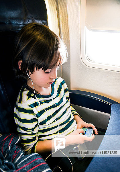 Junge im Flugzeug wählt Musik auf mp3-Player