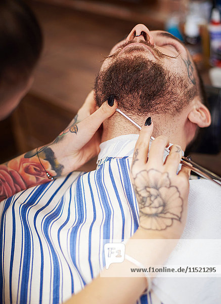Friseur rasiert Bart des Kunden