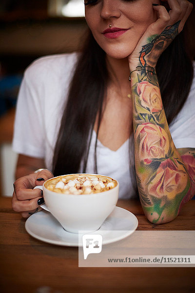 Tattooed woman with cup of hot chocolate