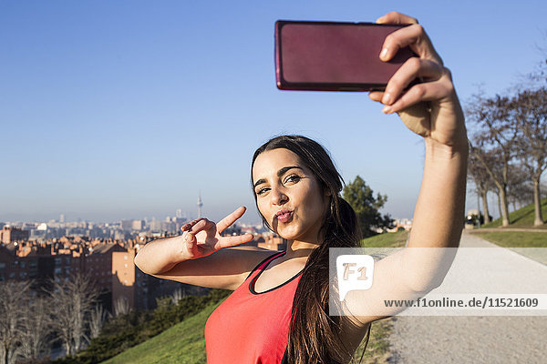 Sportlerin  die mit ihrem Handy für einen Selfie posiert.