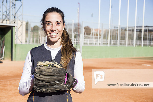 Portrait of smiling female baseball player with a baseball glove