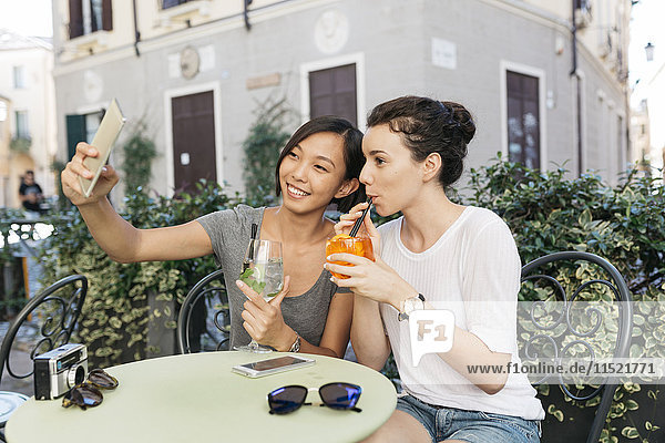 Italien  Padua  zwei junge Frauen  die Selfie im Straßencafé nehmen.