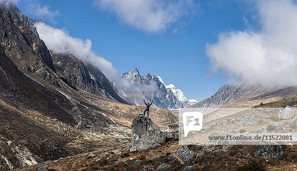 Nepal  Himalaya  Khumbu  Everest-Region  Khunde  Frau jubelnd auf Felsen