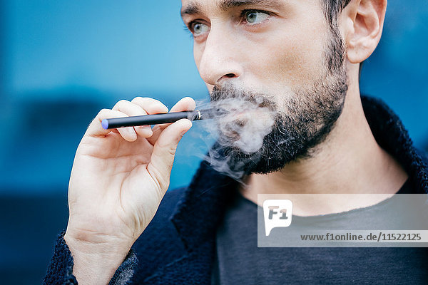Porträt eines Mannes  der eine elektronische Zigarette raucht