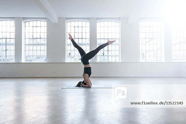 Woman in dance studio doing headstand