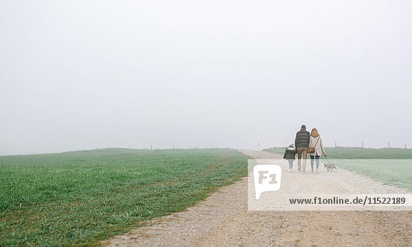 Family walking with dog on a path on a foggy winter day