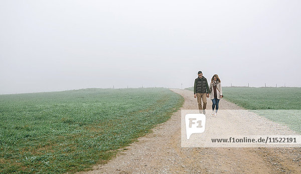 Couple walking on a path on a foggy winter day