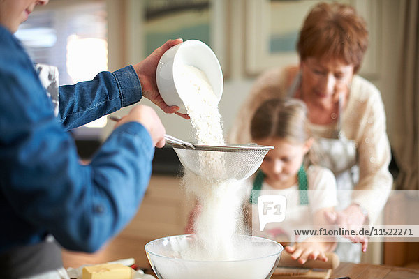 Ältere Frau und Enkelinnen sieben Mehl für Kekse