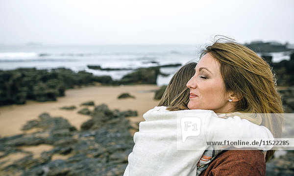 Mother holding daughter on the beach in winter