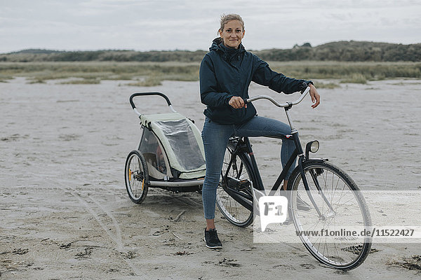 Niederlande  Schiermonnikoog  Frau mit Fahrrad und Anhänger am Strand