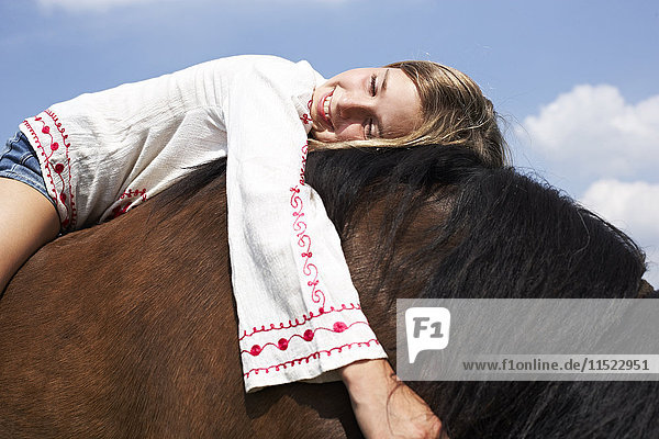 Glückliches Mädchen auf einem Pferd liegend