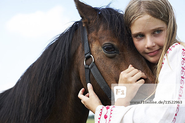 Fröhliches Mädchen umarmt Pferd
