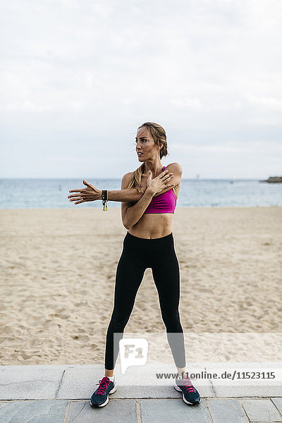 Young woman stretching and warming up for training at the beach