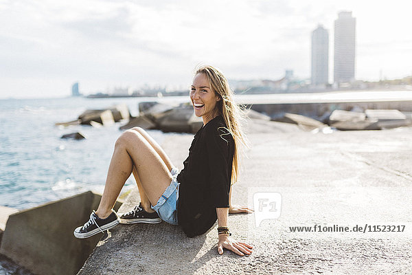 Portrait of happy young woman sitting at the seafront