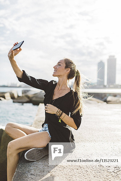 Junge Frau  die einen Selfie an der Strandpromenade nimmt.