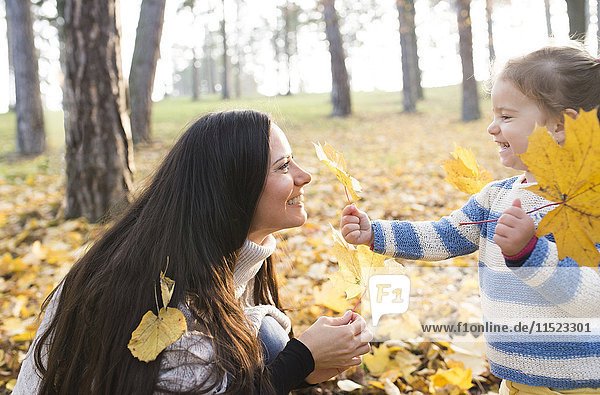 Happy mother with her daughter in autumnal forest
