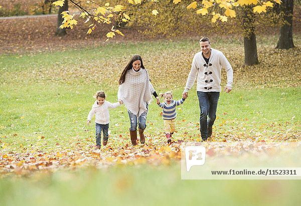 Happy family with two girls walking in autumn leaves
