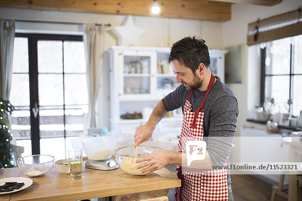 Man standing in kitchen  preparing cake dough