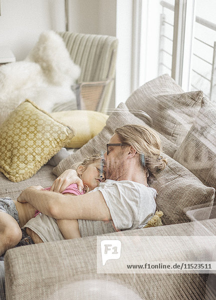 Vater entspannt mit Tochter auf dem Sofa