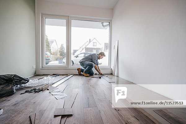 Mature man fitting flooring in new home