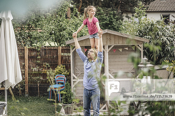 Vater trägt Tochter auf Schultern im Garten
