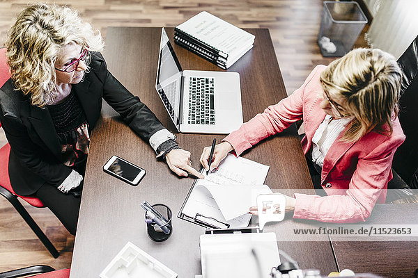 Two businesswomen working on document in office