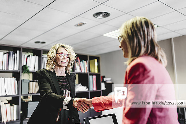 Zwei Geschäftsfrauen beim Händeschütteln im Büro