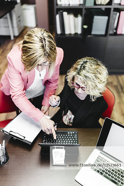 Two businesswomen using laptop at desk in office