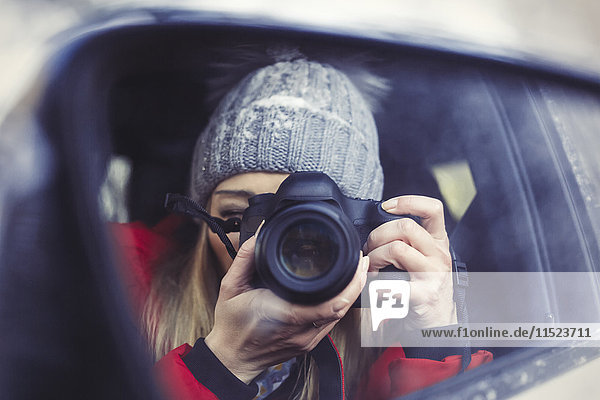 Wing mirror with mirror image of woman taking picture of herself  close-up