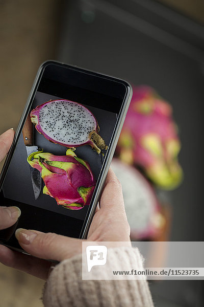 Hand holding cell phone with picture of dragon fruit