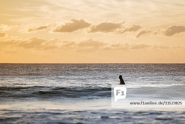 Surfer im Wasser bei Sonnenuntergang