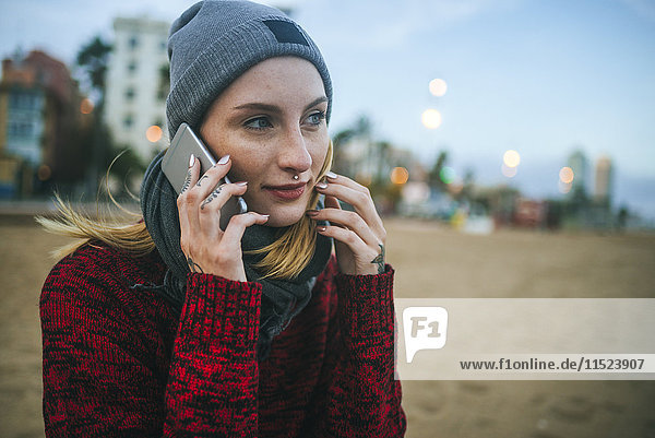 Young woman on the beach in winter on cell phone