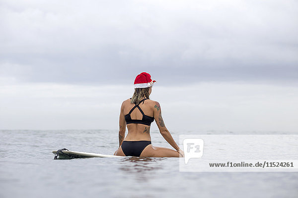 Indonesien  Bali  Frau auf dem Surfbrett mit Weihnachtsmütze