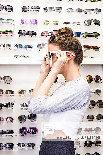 Young woman putting on sunglasses in an optician shop