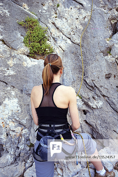 Frau bereitet sich vor  eine Felswand zu erklimmen.