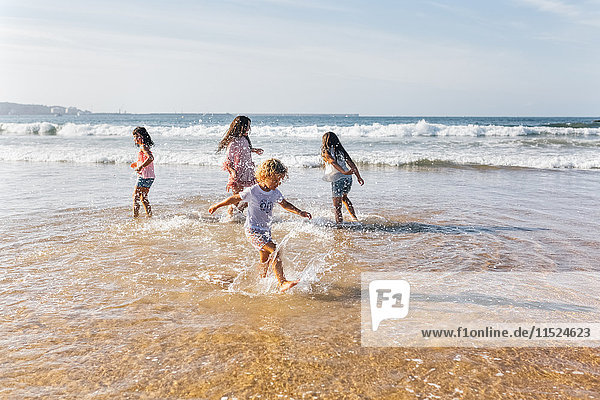Four children splashing with water at seaside