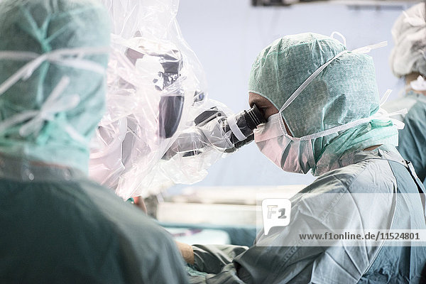 Neurochirurg beim Blick durchs Mikroskop während einer Operation