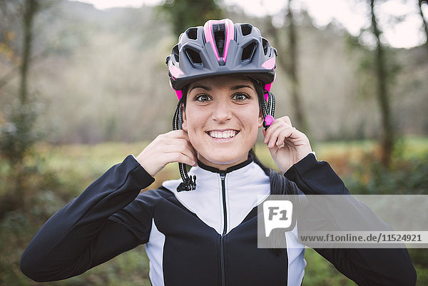 Portrait of smiling woman putting on bicycle helmet