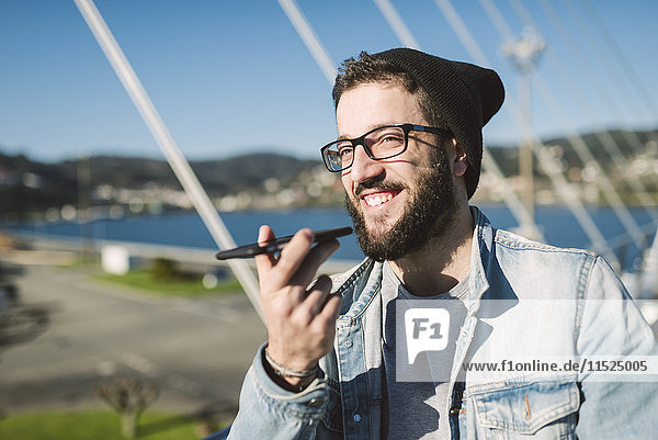 Lächelnder junger Mann mit Smartphone im Freien