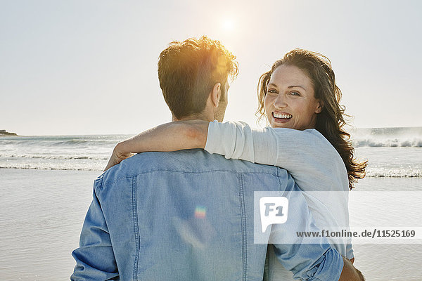 Porträt einer glücklichen Frau mit ihrem Partner am Strand
