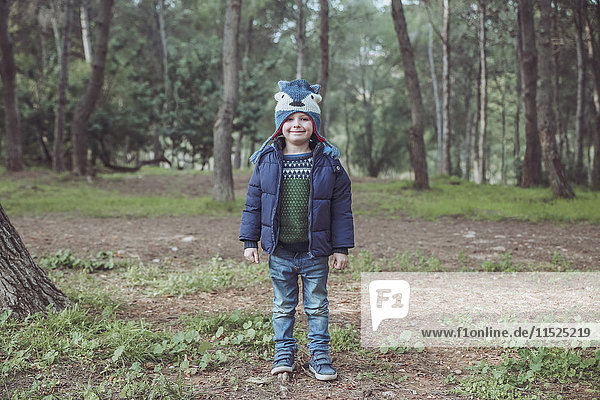 Portrait of smiling boy wearing wooly hat in forest