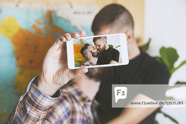 Young gay couple taking a selfie with smartphone  close-up
