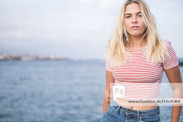 Porträt einer blonden jungen Frau vor dem Meer