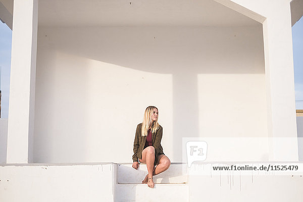 Spanien  Teneriffa  junge blonde Frau auf einer Treppe sitzend